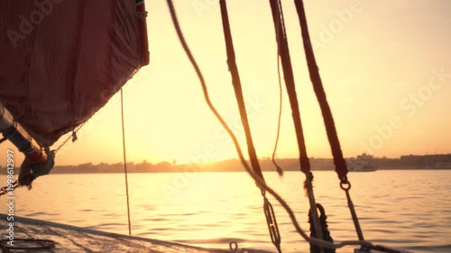 Atmospheric close-up of felucca boat at sunset in Luxor. Close-up shot of a traditional felucca boat on the Nile River at sunset. The camera captures parts of the boat, ropes, and sail