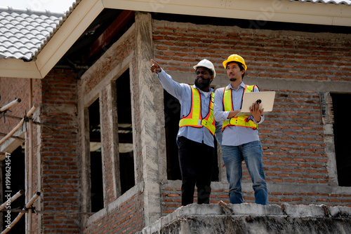 Foto Construction engineers wearing safety helmets analyzing blueprint at building si