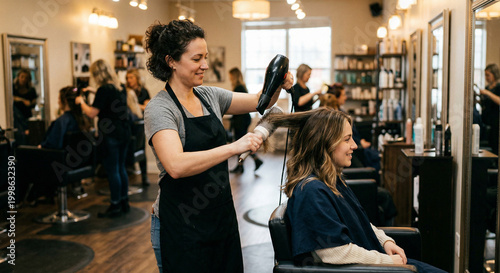 Hairdresser blow-drying a client's hair in a busy salon