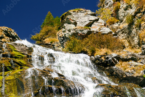 Stunning Capra Waterfall flowing over rocky cliffs in Fagaras mountains. View from Transfagarasan Highway, Romania.