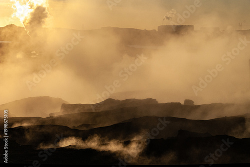 Geothermal steam rising from volcanic landscape in Iceland with dramatic light mist and rugged geothermal terrain