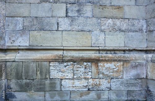 Ancient Medieval Stone Wall Texture with Weathered Sandstone Blocks and Architectural Molding, Historical Cathedral Masonry Background, Rugged Old Fortress Exterior, Authentic Heritage Surface Detail.