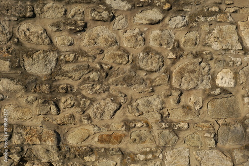 Rustic Warm Tone Stone Wall Texture with Irregular Rock Pattern and Earthy Rubble Masonry, Ancient Medieval Fortress Background, Rural Architecture Surface Detail, Aged Hard Rock Backdrop.