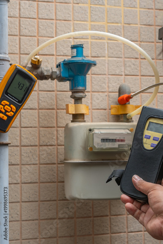 A technician uses professional gas detectors to perform a safety check on a residential gas meter and pipeline system