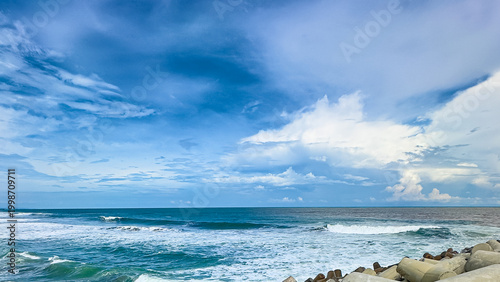 Ocean waves under blue sky with clouds, peaceful seaside landscape