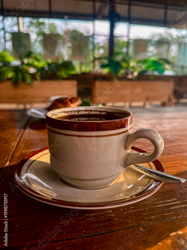 Cup of coffee on wooden table with cozy cafe atmosphere and warm lighting