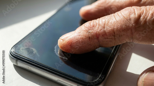 Digital divide elderly hand pressing smartphone touchscreen macro