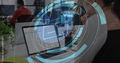 Leaning woman wearing light top examining data on laptop at office, HUD lock overlay visible