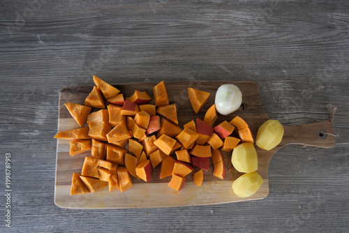 Three Peeled Potatoes and Diced Pumpkin Pieces on Cutting Board, Food Preparation Scene