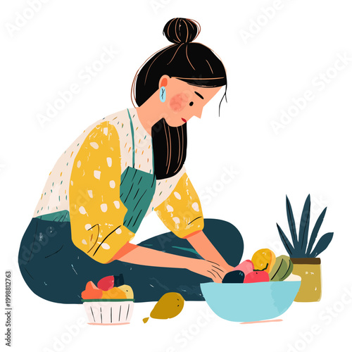 Woman organizes fresh fruit into a bowl while sitting on the floor.