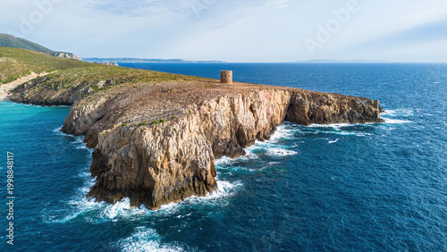 Aerial view of the rugged limestone cliffs and the historic Spanish watchtower at Cala Domestica, Buggerru, Sardinia, Italy
