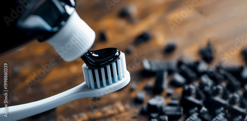 Black charcoal gel toothpaste squeezed onto the bristles on blurred charcoal background