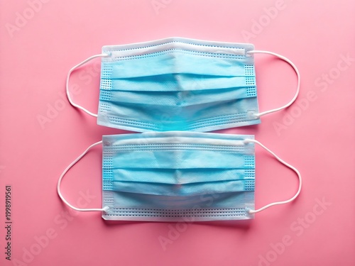 Two blue medical face masks on pink background