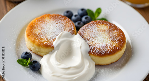 Delicious cheesecakes with cottage cheese, fresh blueberries, sour cream, and powdered sugar on a white plate. A healthy breakfast or dessert. Top view, flat composition. AI generated.
