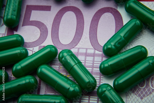 Green capsules on a 500 euros banknote, conceptual image
