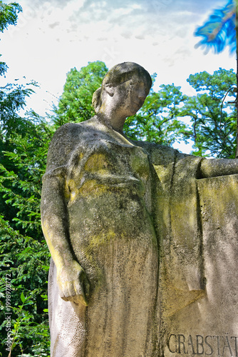 eine Frau in tiefer Trauer an einem Grabstein auf einem Friedhof in Köln