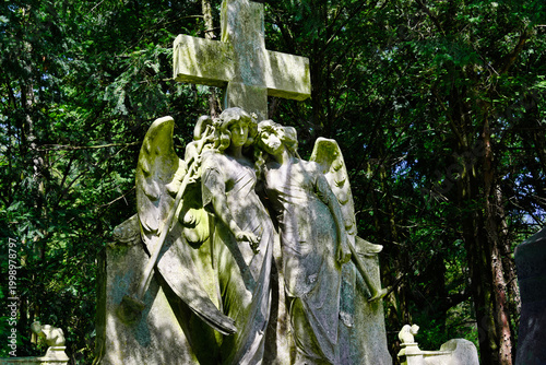 zwei Engel unter einem Steinkreuz auf einem Friedhof in Köln 