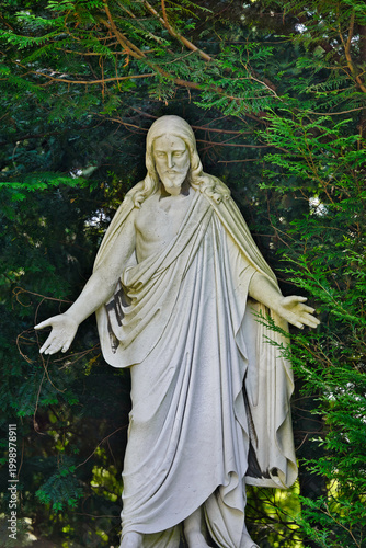 große Jesusfigur mit ausgebreiteten Armen auf einem Friedhof in Köln
