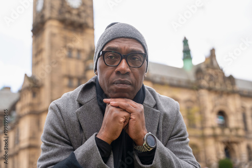 Foto Man in gray coat sits thoughtfully near historical building in city square