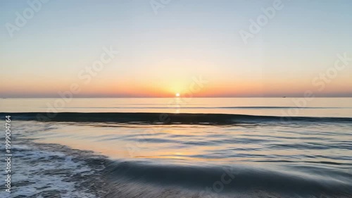 Serene sunset over calm ocean waters with gentle waves in twilight  