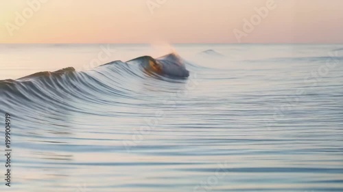 Soft ocean waves gently rolling under pastel sunrise sky  