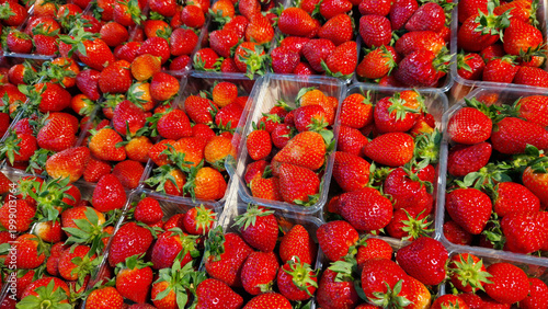 Fresh ripe strawberries in transparent plastic containers. Juicy red berries, top view. Farm strawberry harvest at the market. Bright red berries in packaging, ready for sale. Healthy eating concept