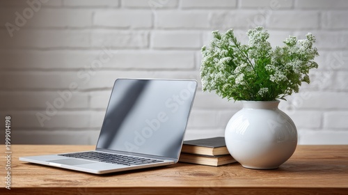 Modern Workspace with Laptop, Potted Plant, and Books on Wooden Desk Against a Bright White Brick Wall for a Stylish and Productive Environment