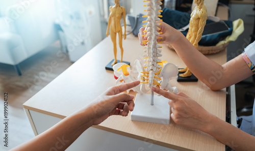 Medical healthcare diagnosis doctor patient consultation spine model on desk in clinic during discussion with specialist for back pain treatment and prevention focus on anatomy detail