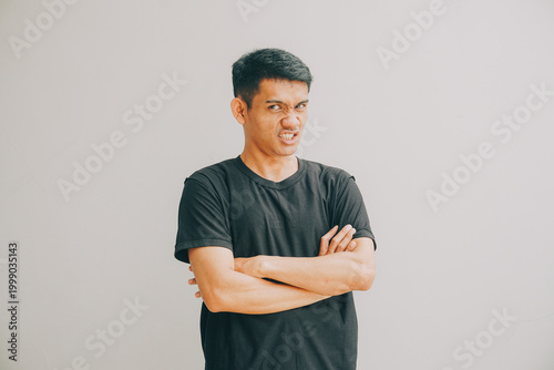 Valokuva man arms crossed expressing displeasure with wrinkled nose and stern face agains