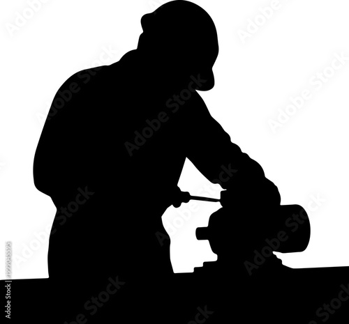 Black silhouette of an industrial worker wearing a hard hat and using a tool on a machine at a workbench
