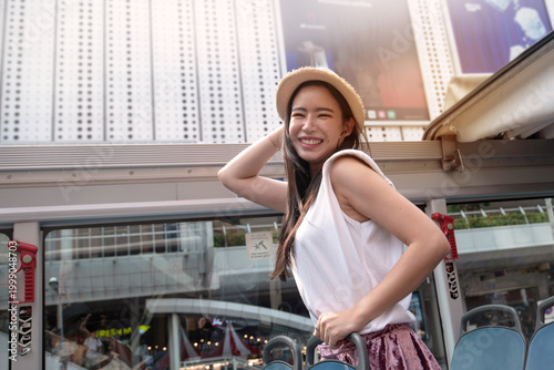 An Asian female tourist enjoyed a tour by open-top bus.