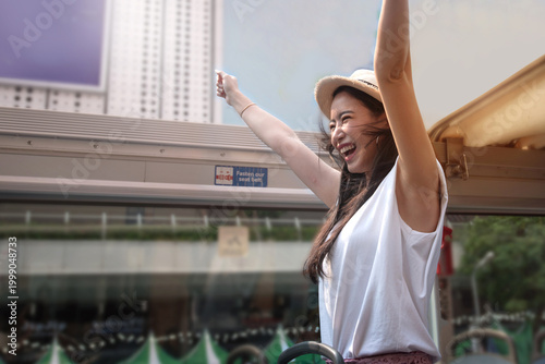 An Asian female tourist enjoyed a tour by open-top bus.