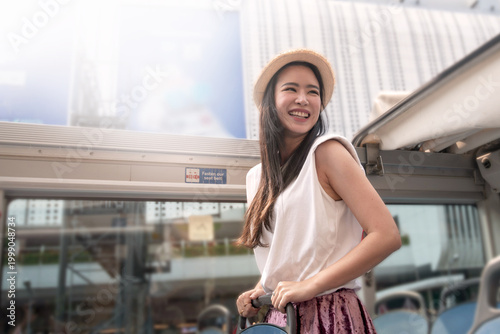 An Asian female tourist enjoyed a tour by open-top bus.