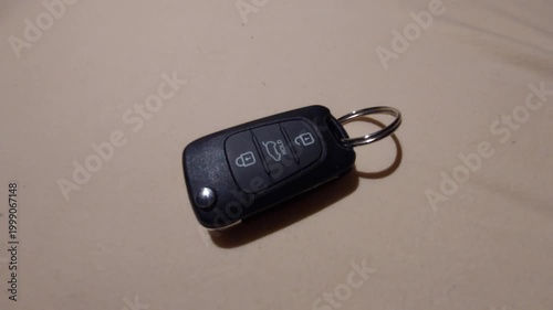 Hand placing a modern car remote key fob on a plain surface