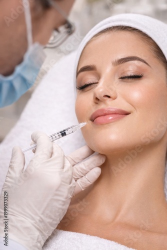 Young woman receiving lip filler injection in a beauty clinic. Close-up of professional lip augmentation procedure with hyaluronic acid. Concept of aesthetic medicine and facial enhancement