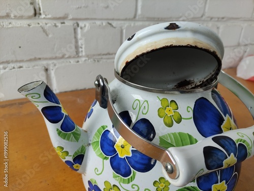 Enamel painted kettle with flowers, lid open and resting on top