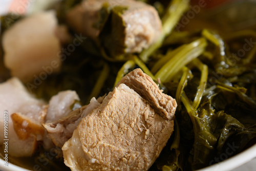 Photos Close up photo of chunks of pork meat boiled with leafy vegetables