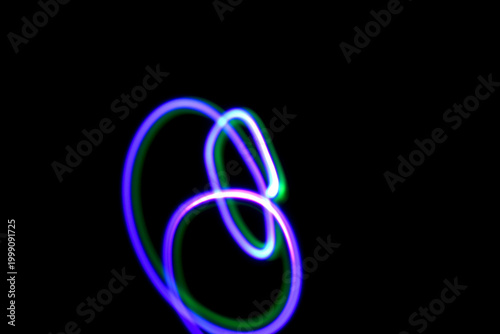 Abstract irregular neon light on a black background. Long exposure. Photograph created using the light painting technique. High-quality photo.