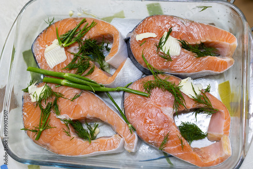 Raw salmon steaks with butter and dill. Salmon steaks in a glass baking dish. Red fish steaks.