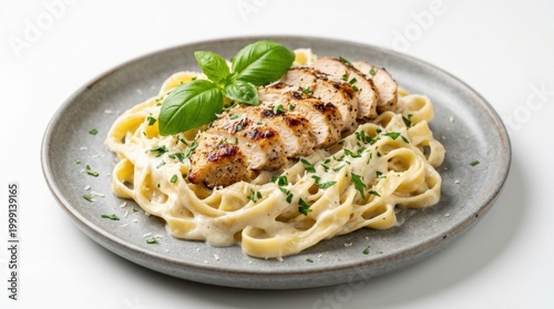 Gourmet fettuccine alfredo with grilled chicken and fresh basil on gray plate