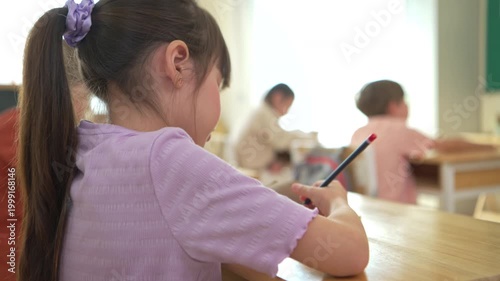 The student is taking notes while being taught by the teacher in the classroom, demonstrating a positive and attentive learning atmosphere in an international school