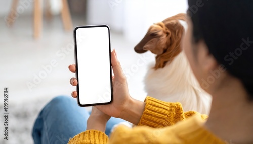 Woman using smartphone with blank screen and dachshund dog.