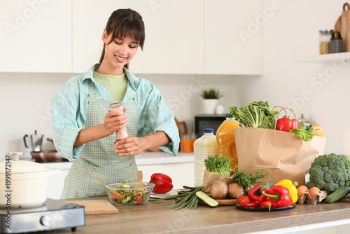 Young woman salting vegetab...