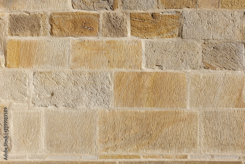 Tableau sur toile Historic sandstone ashlar wall with bush-hammered texture in warm golden tones