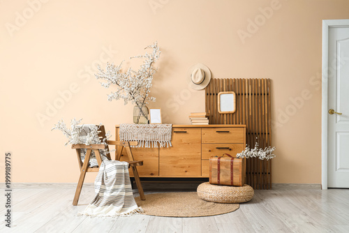 Interior of living room with blossoming branches, chair and commode