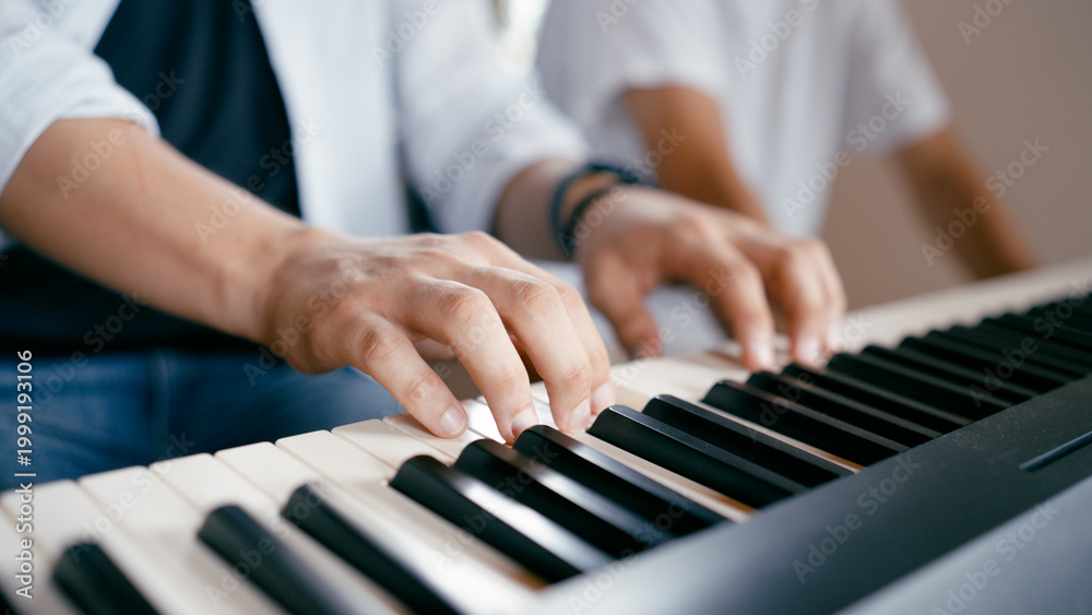Obraz premium Musician hands playing an electronic piano keyboard, practicing music at home or during a lesson. Focus on learning and skill