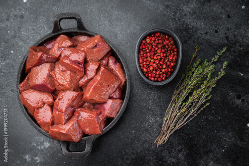 Obraz na płótnie Raw lamb liver pieces in cast iron pan with thyme, mutton organ meat ingredient