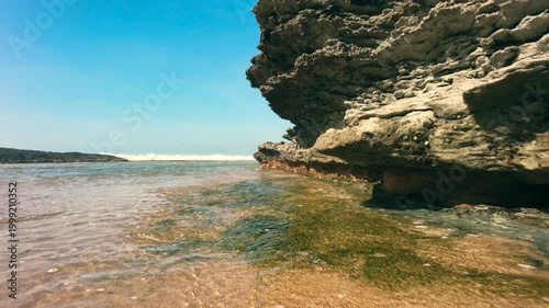 Camera moving slow, close to transparent ocean water with rocks around 