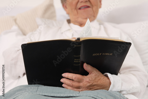 Senior woman in bed reading...