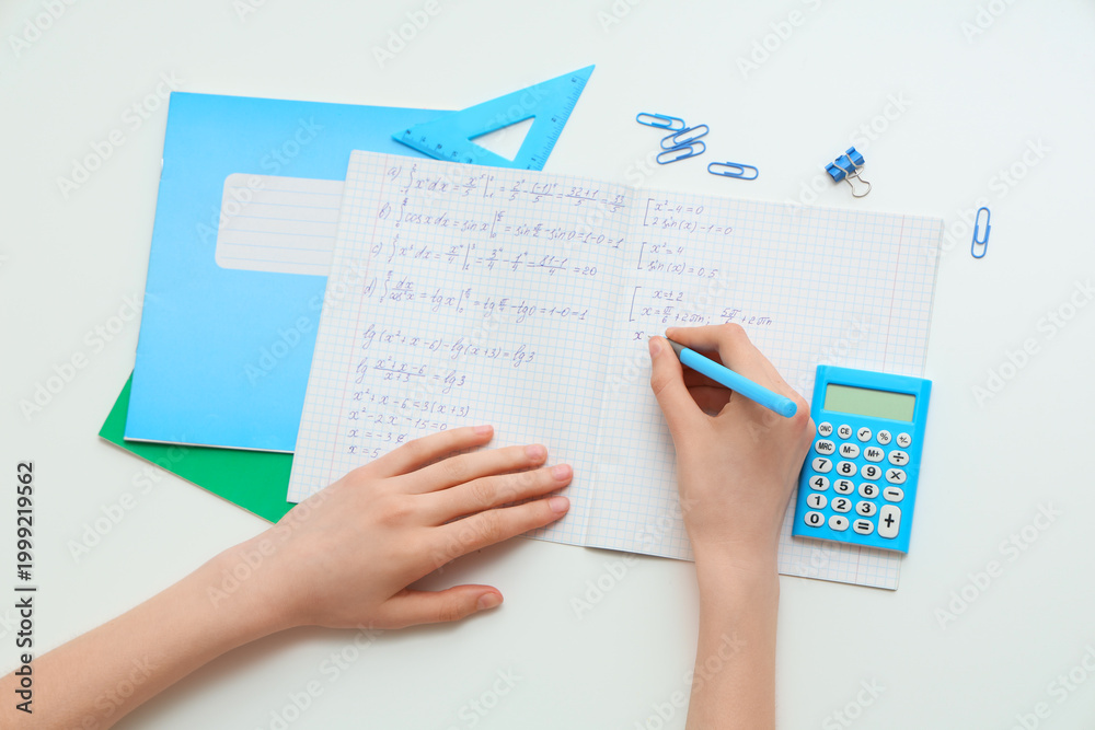 Fototapeta premium Woman writing math formulas in copybook on light background